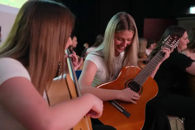 Zwei weibliche Jugendliche spielen auf ihren Gitarren.