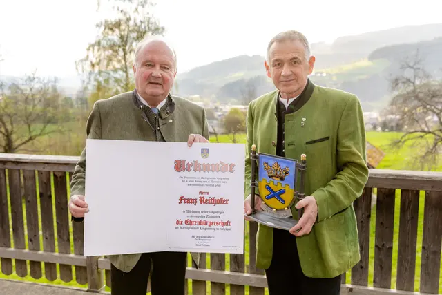 Bgm. Rudolf Hofbauer und Franz Reithofer mit der Ehrenbürgerschaft-Urkunde und einem Gemeindewappen aus Glas. 