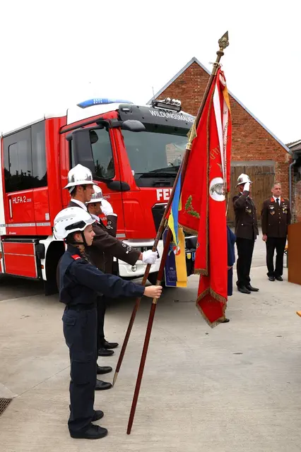 Fahnenträger vor Feuerwehrauto