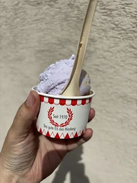 Hand mit Eisbecher und Löffel von vorn