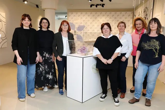Sieben Damen stehen für ein Gruppenfoto im Museum zusammen. In der Mitte steht ein Glaskasten mit Ausstellungsstücken.