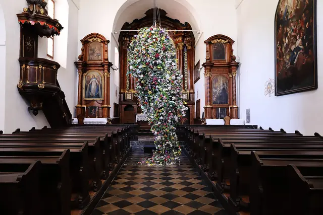Ein riesiges Gesteck aus Kunstblumen hängt in einer Kirche von der Decke.