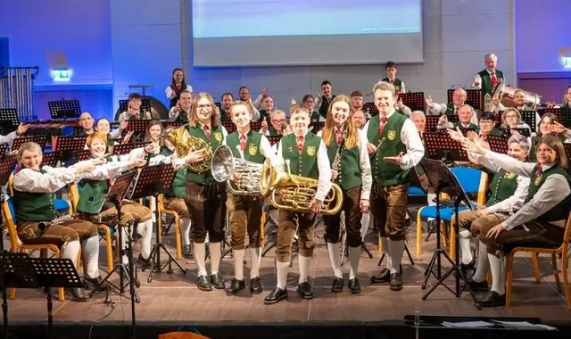 Musikanten auf der Bühne zeigen mit ihren Händen auf die talentierten Jungmusiker.
