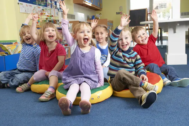 Mehrere Kinder lachen und zeigen mit der Hand auf. 