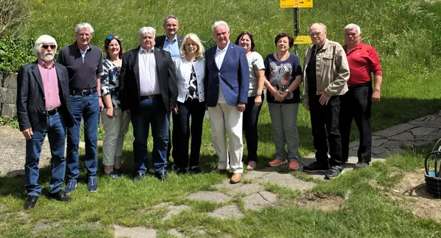 Eine Gruppe von Pensionisten befindet sich auf einer grünen Wiese. 