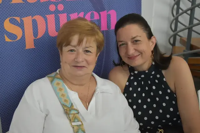 Zwei Frauen lächeln in die Kamera.