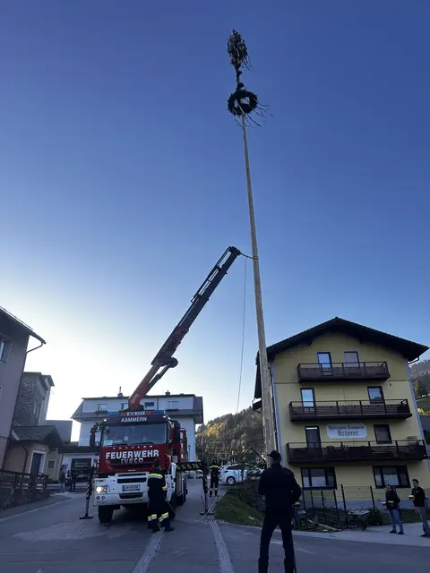 Kranwagen der Feuerwehr stellt Maibaum auf