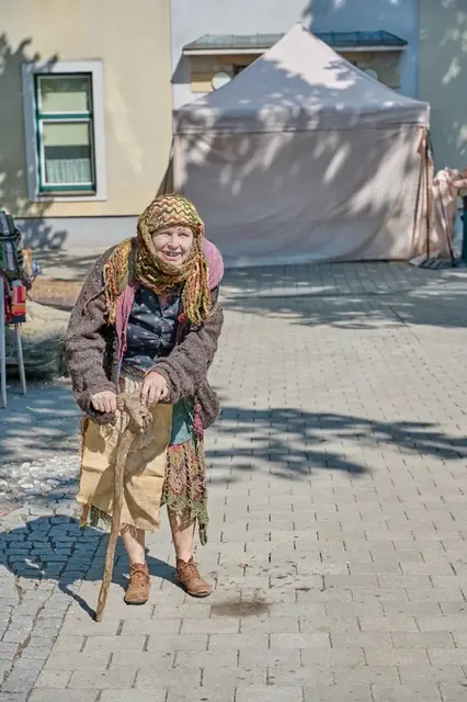 alte gewandete Frau mit Holzgehstock