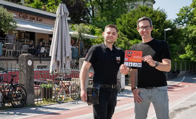 Cafe am Kai macht bei der Aktion „Nette Toilette“ mit
Das Cafe am Kai ist einer von sechs neuen Partnerbetrieben der Aktion „Nette Toilette“. Im Bild v.l.n.r.: Adrian Puraner, Mitarbeiter Cafe am Kai, und Bürgermeister-Stellvertreter Kay-Michael Dankl vor dem Cafe am Kai in Mülln. | Foto: Stadt Salzburg/Alexander Killer