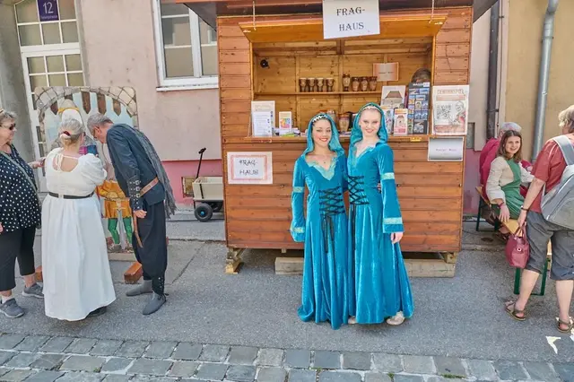 zwei blau gewandete Damen vor dem Fraghaus