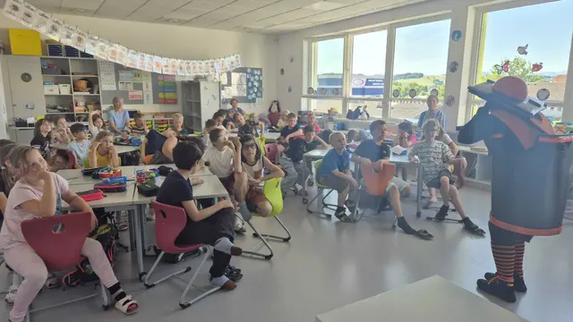 Kinder im Klassenzimmer, die der Schauspielerin mit Abfalltonnenkostüm zuschauen