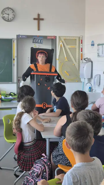 Schauspielerin, als Mülltonne verkleidet, vor einer Schulklasse im Klassenzimmer