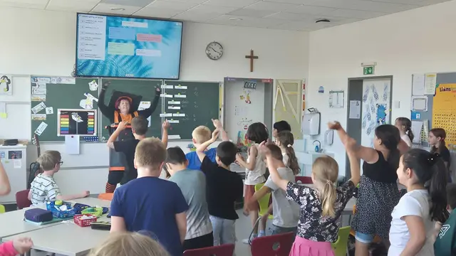 Schulklasse; die Kinder machen mit bei einem Tanz, den die als Restmülltonne verkleidetete Schauspielerin vortanzt.