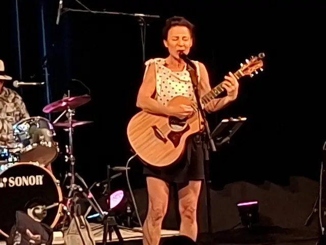 Eine Vokalistin singt auf einer Bühne.