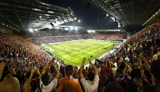 Menschen jubeln in einem vollen Fußball-Stadion.