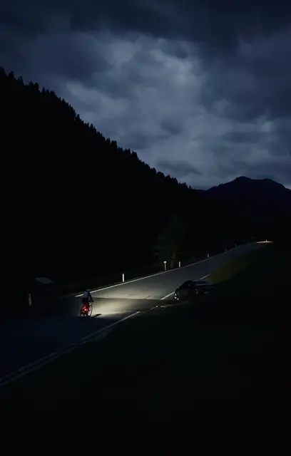 Radfahrerin auf Landstraße bei Nacht