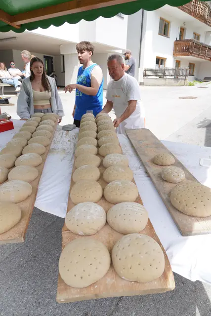 Familie und Helfer arbeiten beim Backofenfest Hand in Hand.