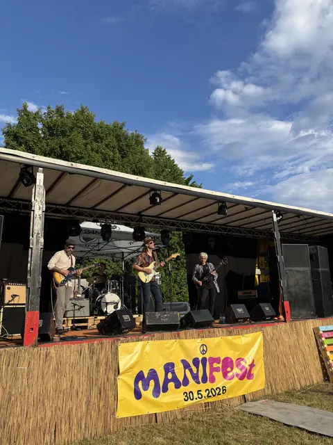 Band auf Bühne mit Plakat: ManiFest 30.5.2026