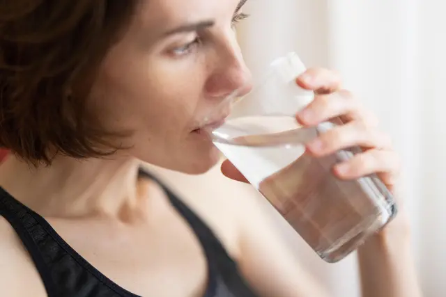 Frau trinkt Wasser aus einem Glas