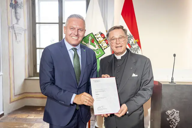Ein Mann überreicht einem anderen Mann eine Urkunde.