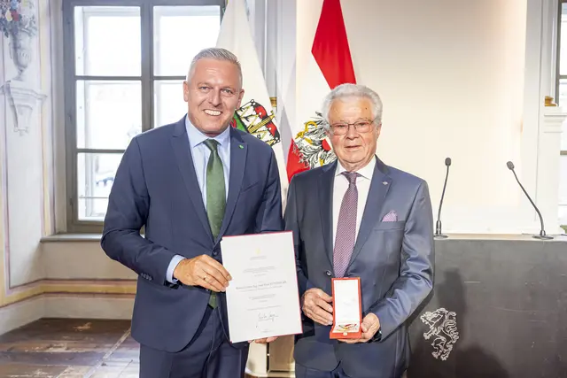 Ein Mann überreicht einem anderen Mann eine Urkunde.