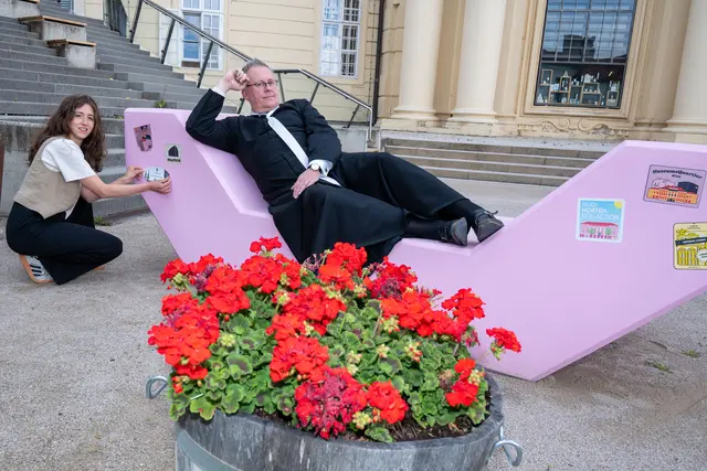 Augustiner-Chorherr Alipius Müller testet die Qualitäten des Enzi vor der Sala terrena des Stiftes Klosterneuburg während Magdalena Ginsthofer von der Kulturabteilung des Stiftes den Destinations-Sticker anbringt. | Foto: Klosterneuburg/Walter Hanzmann