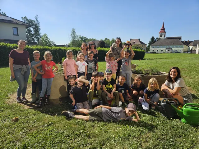 Eine Gruppe Schüler ist stehend, sitzend oder liegend in einer Wiese zu sehen.