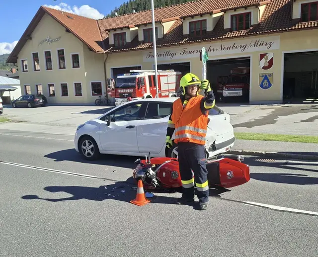 Feuerwehrmann steht vor einem verunfallten Motorrad und regelt den Verkehr