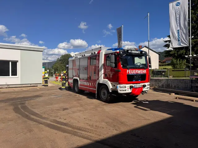 Feuerwehrauto und Einsatzkräfte stehen vor einem Industriebetrieb