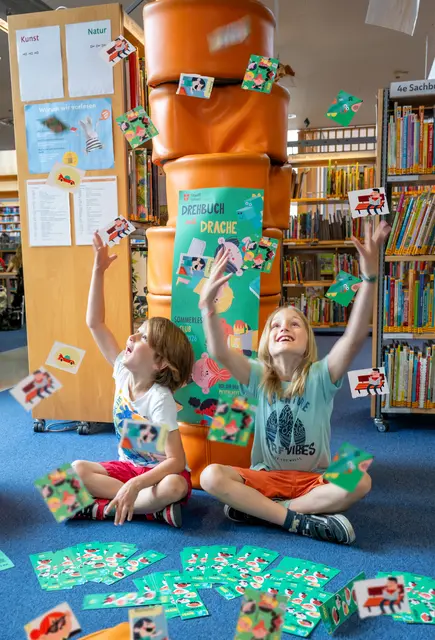 Die Geschichte im Pickerlbuch heißt „Drehbuch mit Drache“ und begleitet eine bunte Freundesrunde auf ihrem chaotischen Versuch, einen Film zu drehen – und ja, ein Drache spielt dabei auch eine Rolle. | Foto: Stadt Wien Büchereien / Natalie Stephan