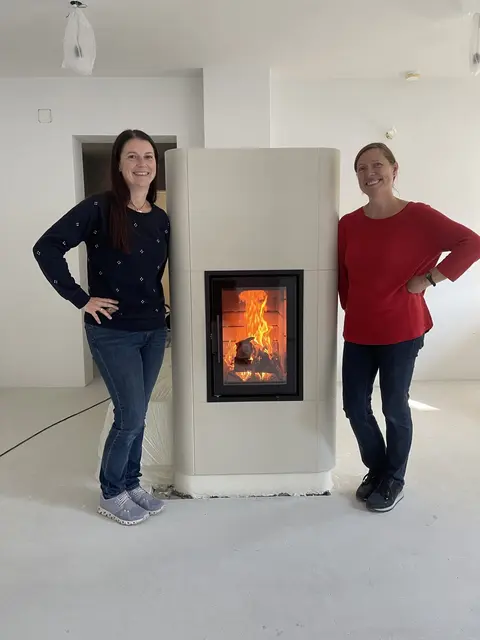 Zwei Frauen neben Kachelofen