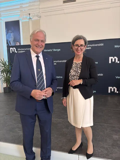 2 Personen stehen vor einem Transparent