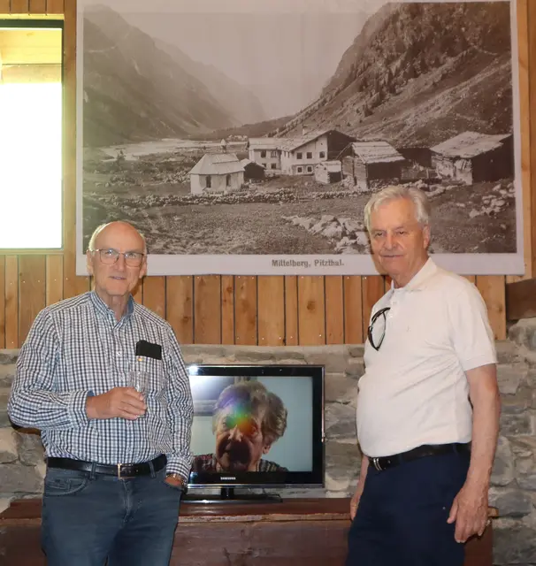 Künstler und Autor Willi Pechtl (rechts) mit einem der beiden Filme der Ausstellung "Faszination Fotografie" und einer Fotografie von St. Leohard im Pitztal im Hintergrund.  | Foto: Tatschl
