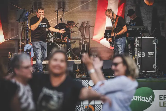 Menschen tanzen vor einer Bühne, auf der Musiker stehen
