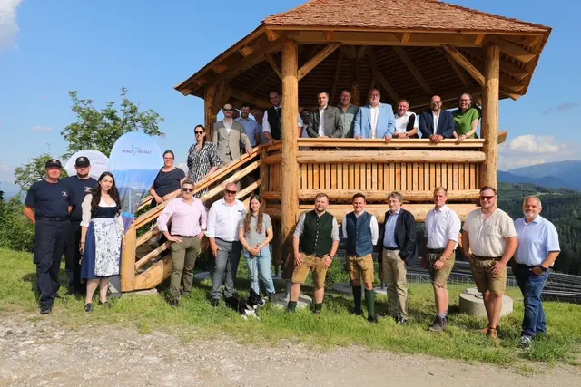 Menschen stehen in und um einen Holzpavillon