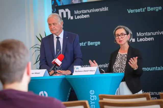 Ein Mann und eine Frau stehen an Rednerpulten vor einem Transparent