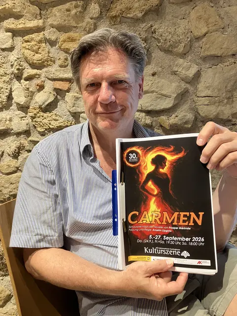 Anselm Lipgens mit dem Plakat, das für das Septembertheater mit der Welturaufführung des Schauspiels "Carmen" wirbt. Das Schauspiel stammt aus der Feder von Anselm Lipgens, der auch Regie führt und als Grundlage die gleichnamige Novelle von Prosper Mèrimée hat. | Foto: Stockmann