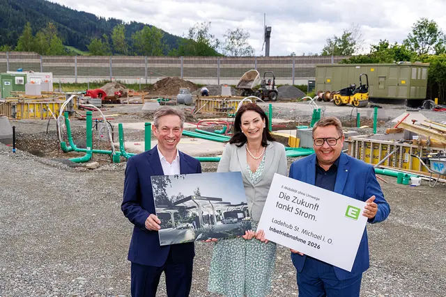 2 Männer und 1 Frau stehen mit Schildern auf einer Baustelle