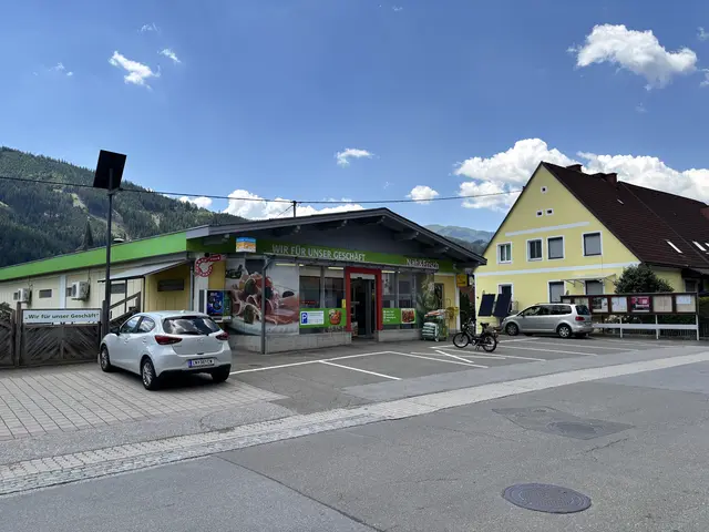 Außenansicht von einem KAufhaus und ein Auto steht am Parkplatz davor