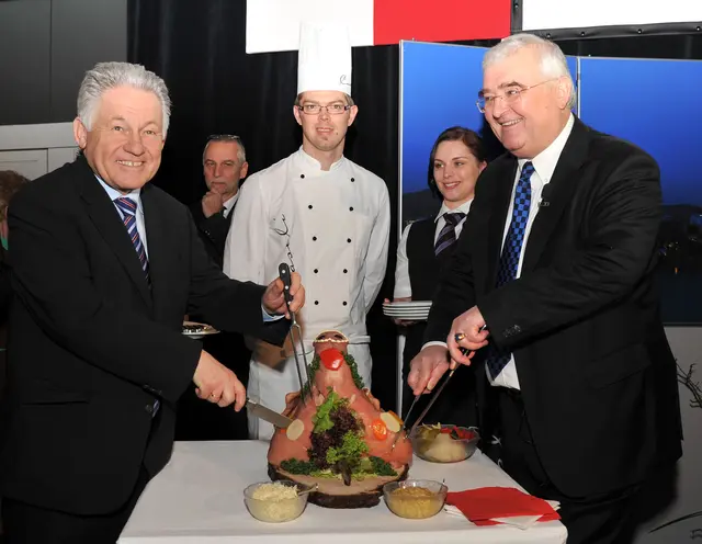 Josef Pühringer (links) und Franz Dobusch (rechts) beim Anschneiden des Schweinskopfes beim Linzer Neujahrsempfang. | Foto: Stadt Linz