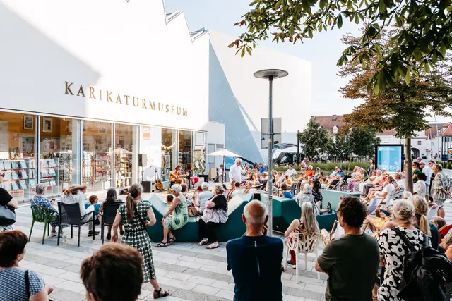 Erstes Kremser Platzkonzert beim Karikaturmuseum Krems von „Peter Kern Solo“ mit zahlreichen Besucher:innen bei Sommerflair | Foto: Ideenladen / Sebastian Streibel