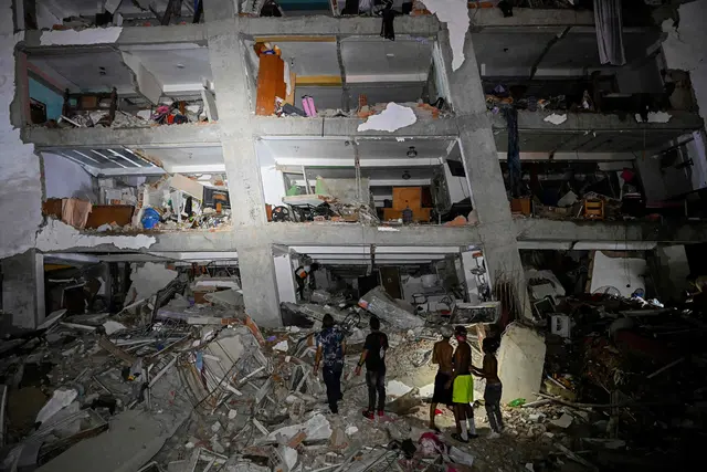 Menschen stehen zwischen den Trümmern eines durch das Erdbeben beschädigten Gebäudes in Catia La Mar im Bundesstaat La Guaira, rund 30 Kilometer nordwestlich von Caracas. | Foto: APA-Images / AFP / FEDERICO PARRA