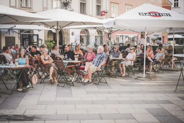 Viele Menschen sitzen in einem Gastgarten