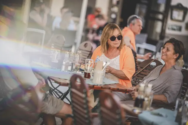 2 Frauen sitzen an einem Tisch und unterhalten sich