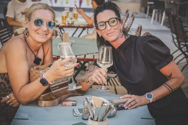 2 Frauen stoßen mit einem Glas Wein an