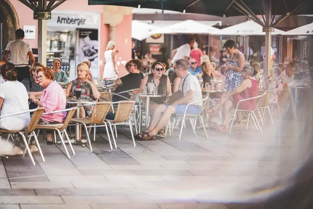 Viele Menschen sitzen in einem Gastgarten