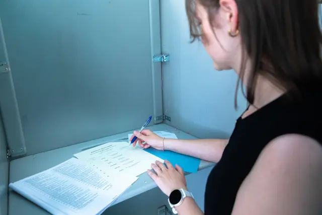 Frau in Wahlkabine bei der Stimmabgabe.