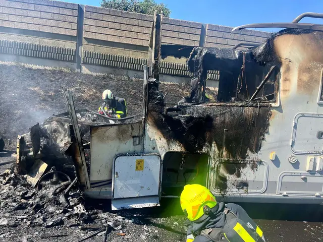 2 Feuerwehrmänner mit Atemschutz löschen Glutnester eines ausgebrannten wohnmobils