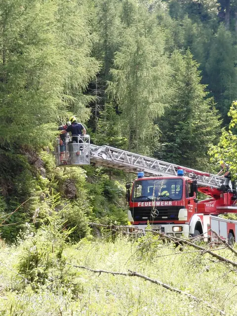 Ein Feuerwehrmann steht auf der Drehleiter des Einsatzwagens