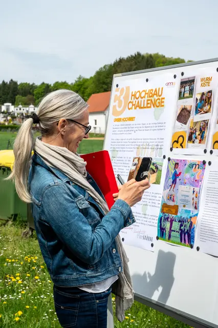 Eine Frau fotografiert begeistert die Infotafel mit Zeichnungen der Schüler.